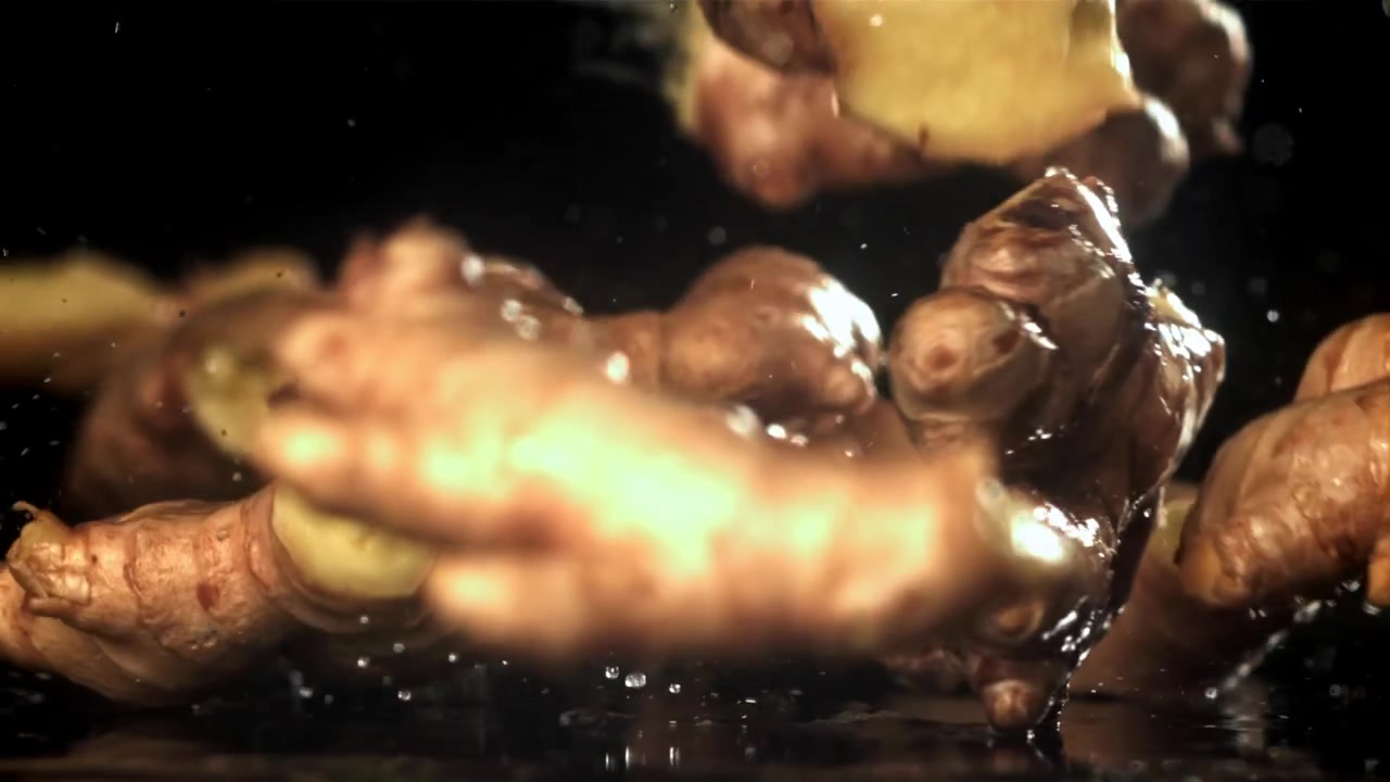 Radici di zenzero fresche che cadono in acqua al rallentatore