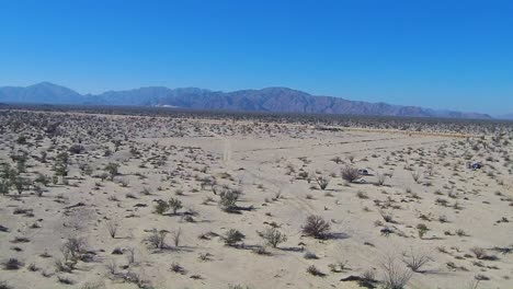 view of a drone flying back over a desert field to a mountain