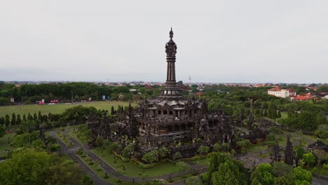 this drone video captures the majestic bajra sandhi monument in renon, bali, standing tall in the center of a large park, surrounded by green lawns, trees, and peaceful walking paths.