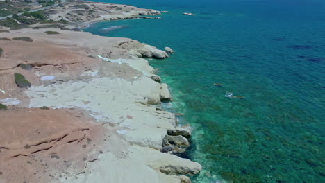 tomada aérea de un dron de las claras olas azules del mar chocando contra las rocas en las costas de chipre