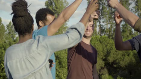 amigos sonrientes haciendo sonar botellas mientras bailan en una fiesta