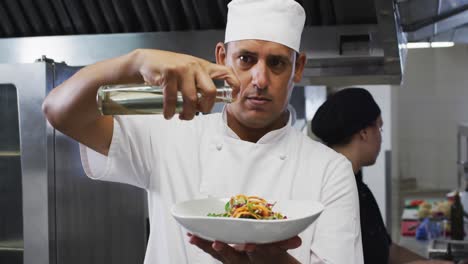 cocinero caucásico adornando platos y sonriendo en la cocina del restaurante