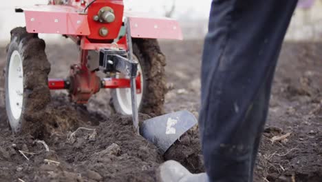 Close-Up-view-of-a-cultivator-tiller-preparing-garden-soil,-new-seeding-season-on-organic-home-vegetable-farm.-Man-pooling-it