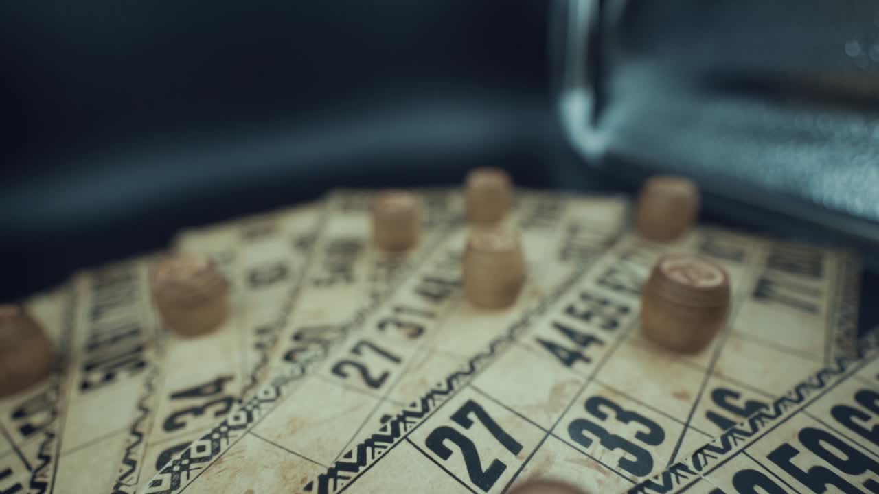 Crane backwards shot of a Bingo desk lottery game, vintage cards with numbers, wooden chips, super slow motion 120 fps, studio lights