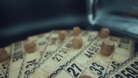 crane backwards shot of a bingo desk lottery game, vintage cards with numbers, wooden chips, super slow motion 120 fps, studio lights