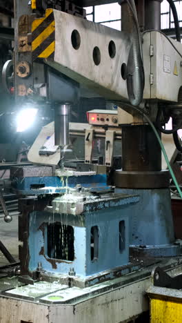vertical - lubricated drill used in factory workshop to drill through metal