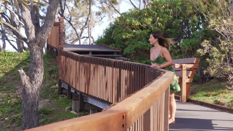 sexy girl leaning on wooden fence feeling the fresh air from ocean -tourist attraction in north gorge walk, point lookout, qld, australia