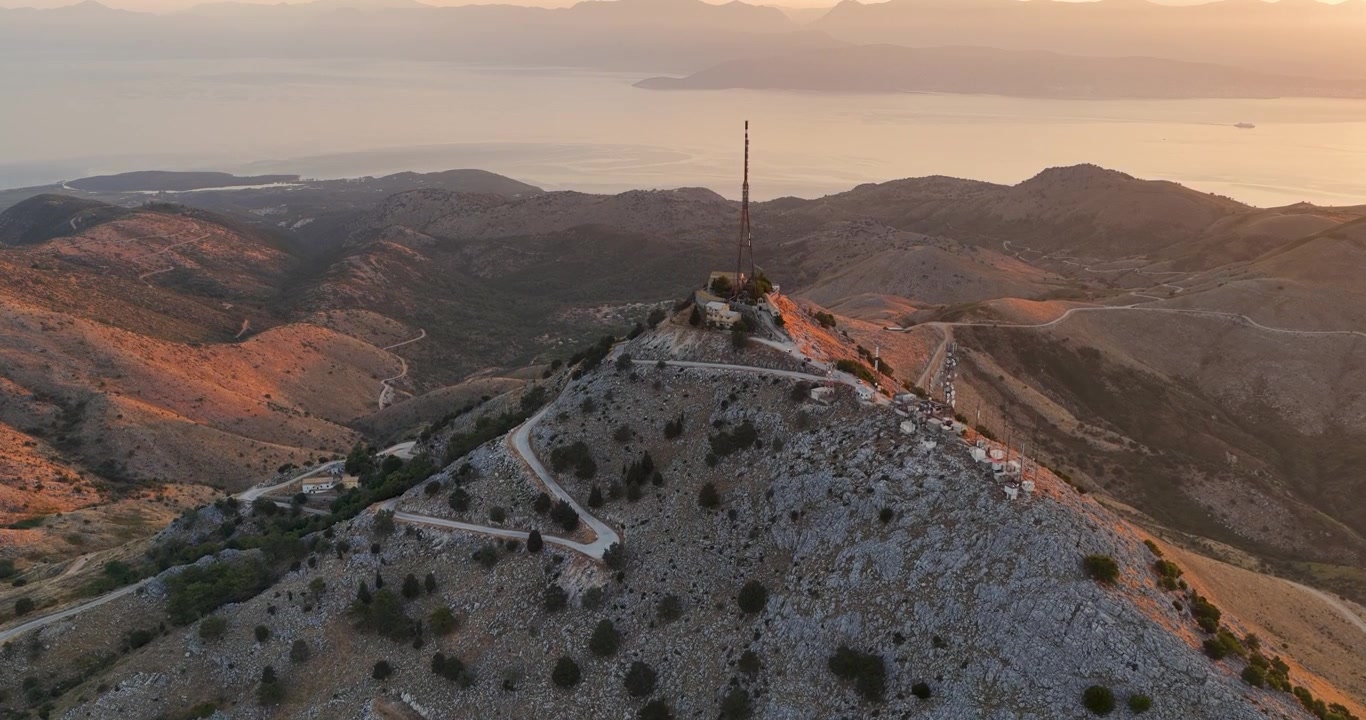 Vista aerea della cima del Monte Pantokrator con strada tortuosa e antenna radio, la vetta più alta di Corfù, Grecia, durante il tramonto all'ora d'oro sul mare