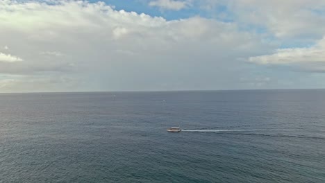 Aerial-view-of-tour-boat-cruising-along-Pacific-ocean