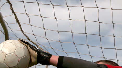 goalkeeper in red saving a goal during a game