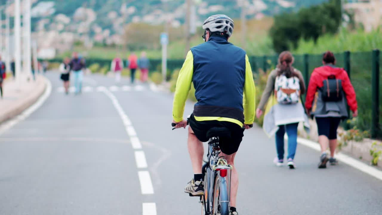 Antibes, France - 20 July, 2024: Man cycling and people walking on the streets of the city centre