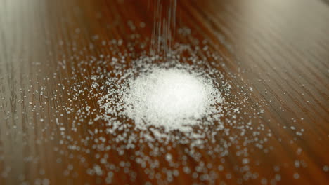 close up slow motion of granulated sugar being poured onto a table