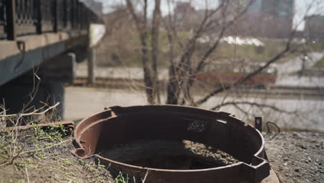 close-up view of a rusty metal object with a railway in the background, showcasing a train passing alongside other cars