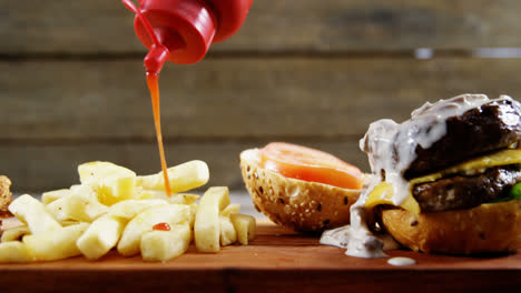 ketchup being squeezed over hamburger on tray