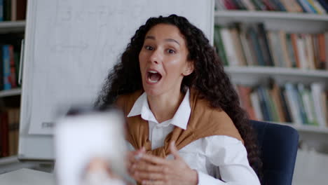 woman teaching online via video call with whiteboard and bookshelves