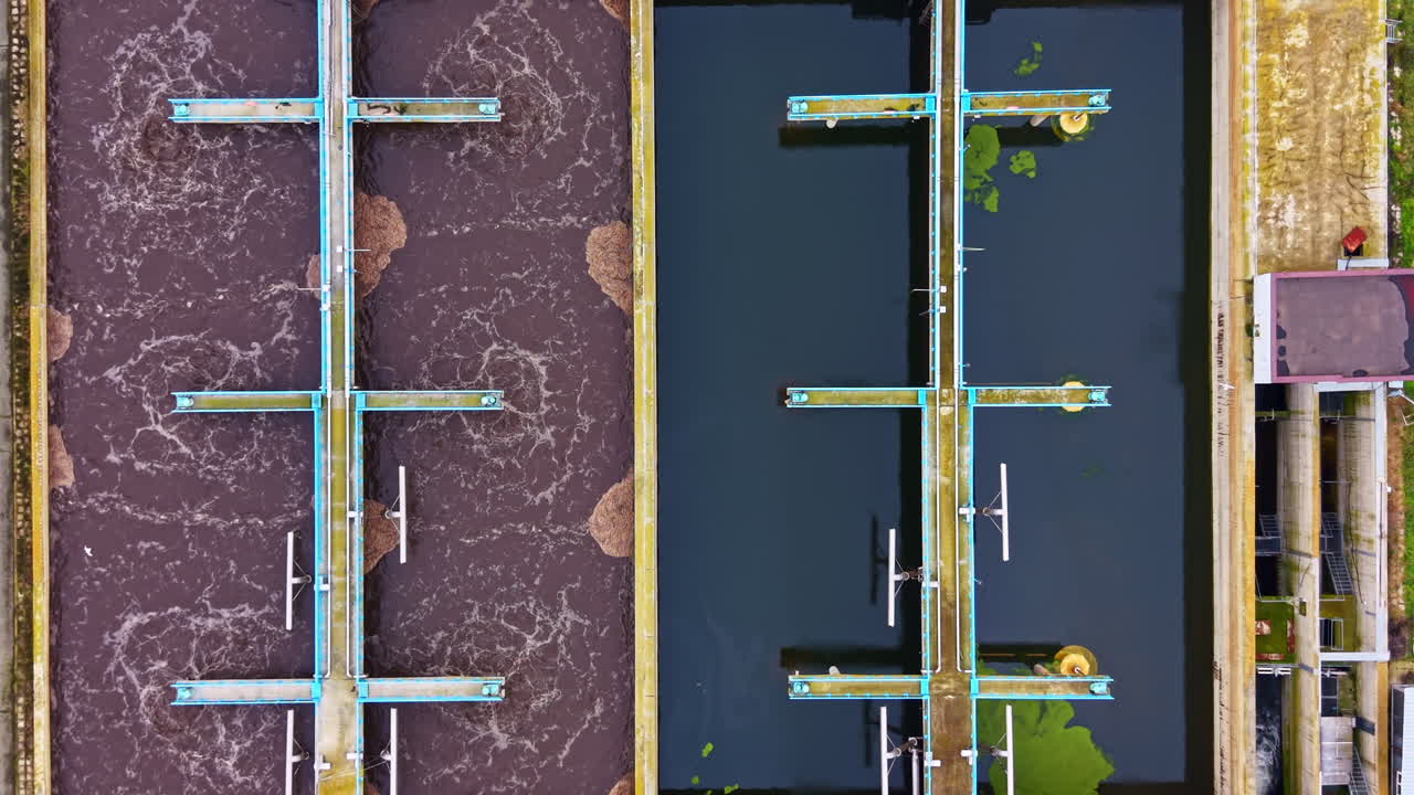 Wastewater treatment process is shown from above in a facility that handles water for a city located in a developed region of the world in daylight