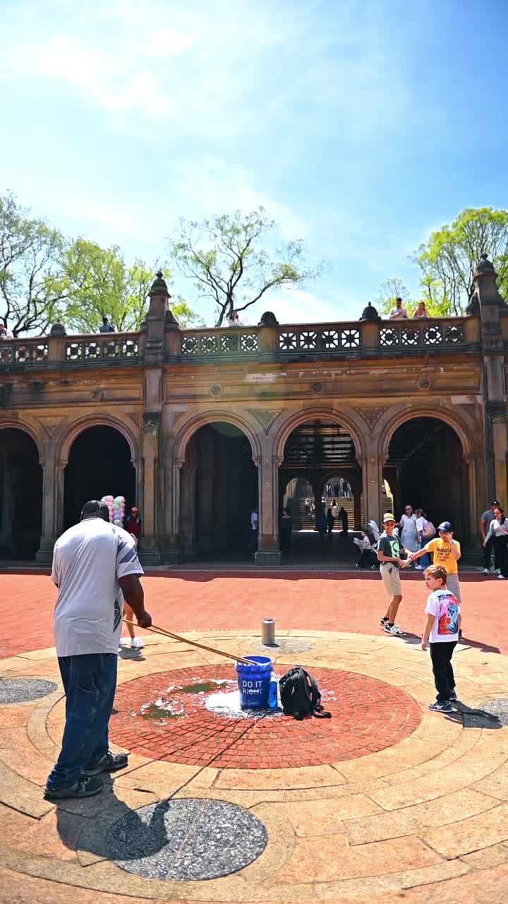 New York, USA, 1 agosto 2025: artista di strada che intrattiene i bambini a Bethesda Terrace a Central Park. Un uomo fa roteare delle lunghe corde mentre i bambini corrono e ridono nella piazza.