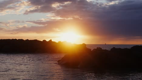 sunset over the ocean with rocks