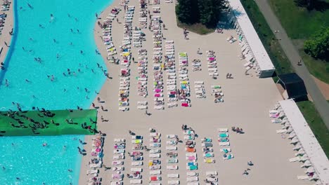 Vuelo-Aéreo-Sobre-La-Playa-Mucha-Gente-Está-Tomando-El-Sol-Nadando-En-La-Piscina