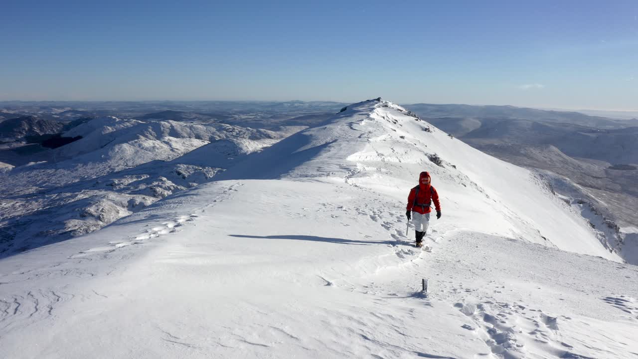 Alpinista stanca che raggiunge la cima di una vetta innevata