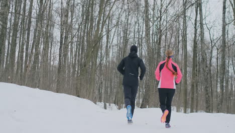 a beautiful woman and a man are running in the forest in winter proper nutrition and a healthy lifestyle. slow motion.