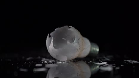 Incandescent-tungsten-lamp-broken-on-small-pieces-of-glass,-isolated-on-black-background