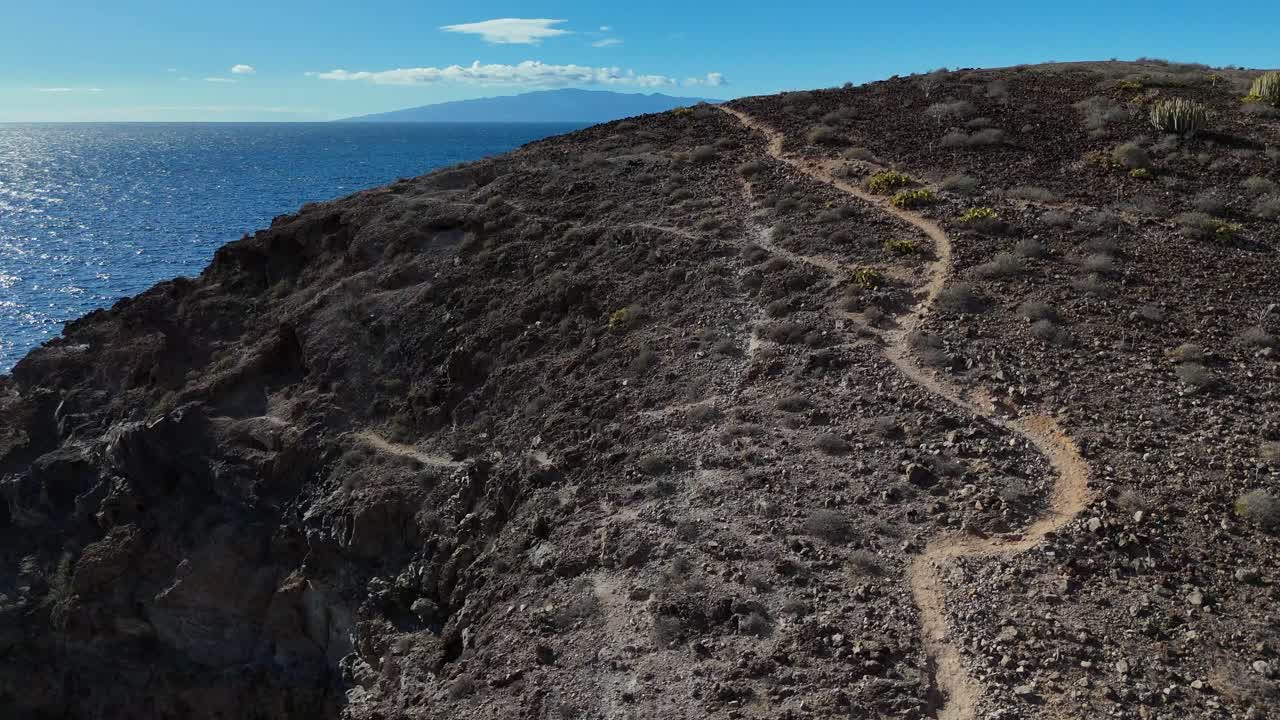un escarpado sendero volcánico en tenerife, islas canarias, con vistas al océano y a la gomera