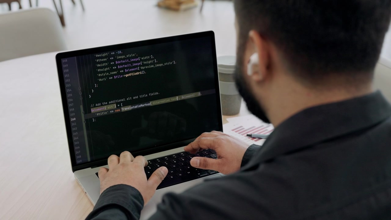 Software Developer Writing Code on Laptop in Modern Office