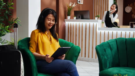 Asiatische-Frau-überprüft-Webseiten-Auf-Einem-Tablet-In-Der-Hotellobby