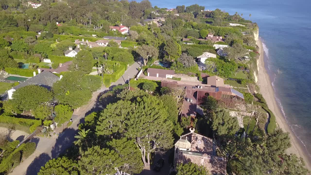 Bird's Eye View Drone Shot of Sprawling Mansions in Malibu, California With the Santa Monica Mountains in the Background at Sunset on a Beautiful Day With Crystal Clear Water