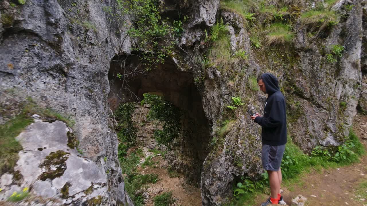 Aerial view of a cave with a man piloting a drone near Uj&euml;vara and Peshtur&euml;s waterfalls in Albania