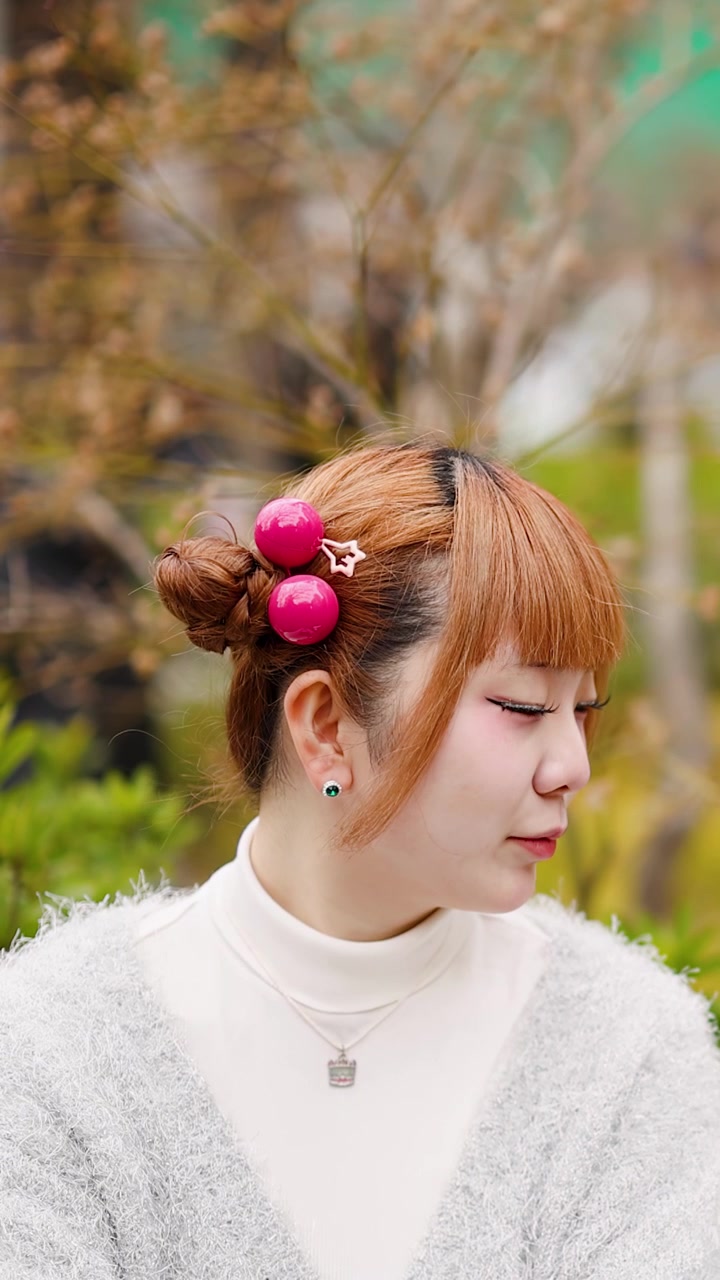 東京の原宿で、カラフルなヘアアクセサリーをつけ微笑むおしゃれなアジア人女性のクローズアップ。
