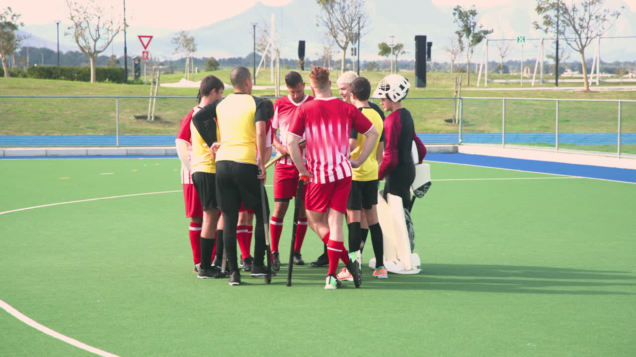 male hockey team huddling on field, discussing strategy before game