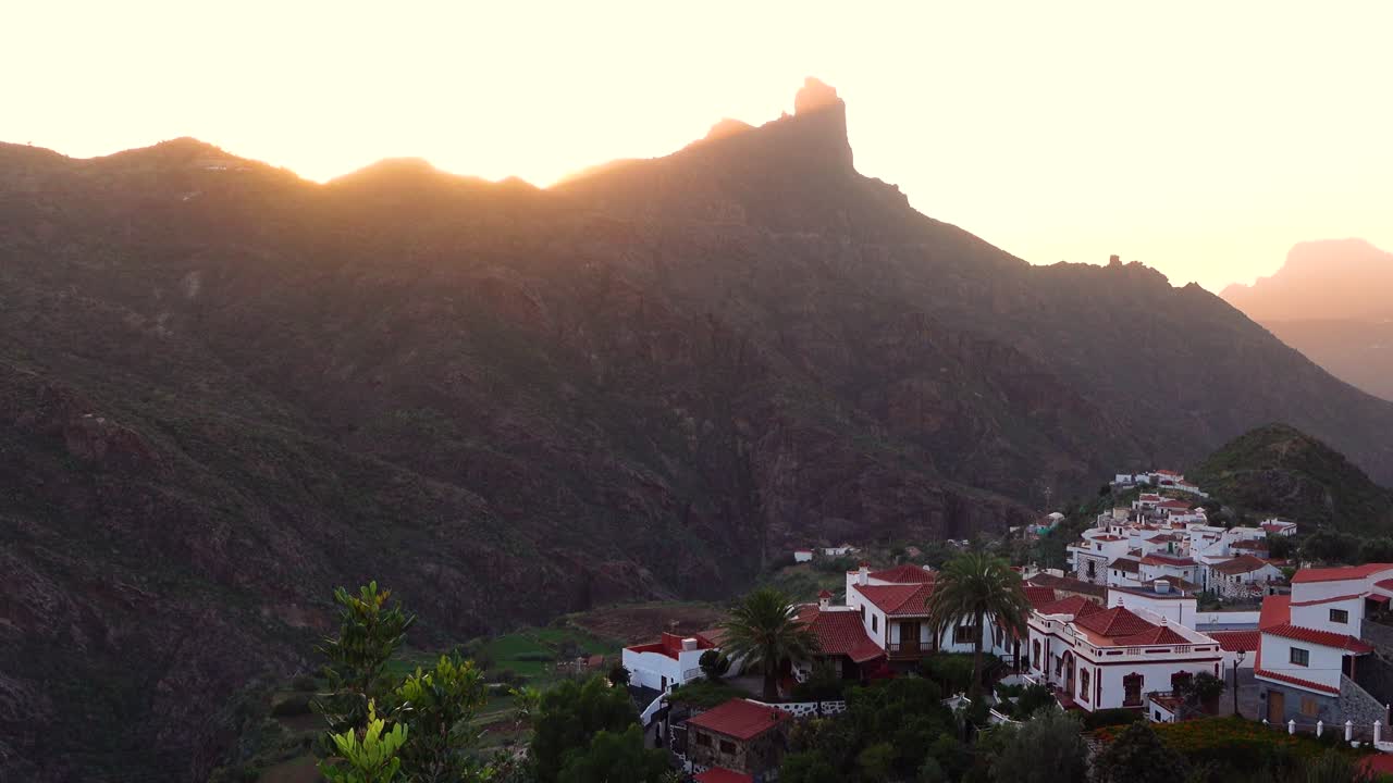 majestuosa puesta de sol en el pequeño pueblo de montaña tejeda en gran canaria con puesta de sol detrás de roque bentayga y creando una hermosa luz vista desde arriba con vistas a las casas blancas y la ladera de la montaña