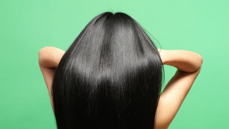 close up back view of a woman using her hands flipping her long black and blond straight healthy hair in the green screen background studio