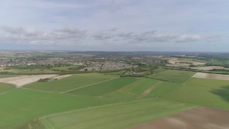 wide aerial tracking forward toward the town of poundbury, just outside of dorchester, summer weather, fields are vibrant