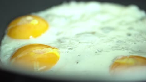 cooking three fried eggs in a pan