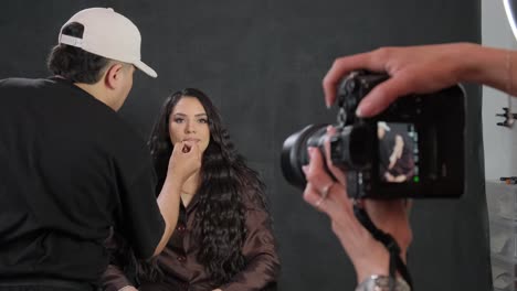 a photographer films how a makeup artist paints the lips of a blackhaired model a photographer films how a makeup artist paints the lips of a blackhaired model high quality footage