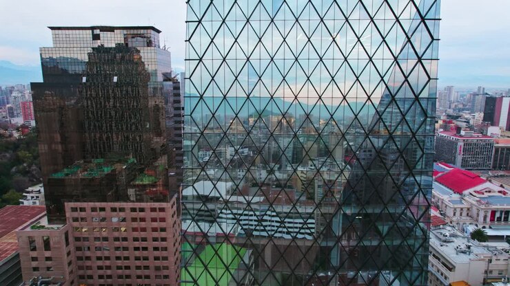 Ripresa con drone in discesa di un edificio di vetro a forma di diamante nel centro di Santiago, architettura antica e moderna.