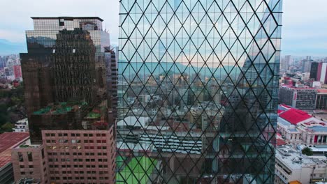 drone shot descending a diamond-shaped glass building in downtown santiago, ancient and modern architecture