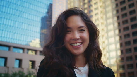 brunette girl laughing on camera closeup. smiling asian woman stand on street.