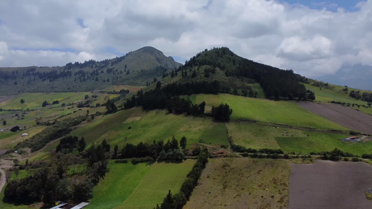 Drone aereo che segue una cima boscosa con fattorie e campi sottostanti