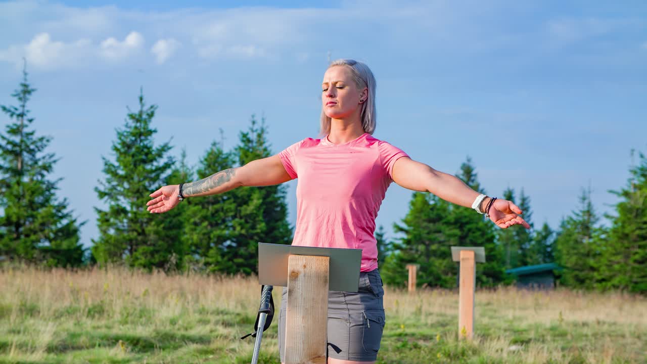 Una donna a braccia aperte in piedi su un punto energetico su una collina.