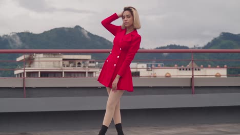 On-a-Port-of-Spain-rooftop,-a-young-girl-with-Hispanic-heritage-wears-a-red-dress-against-the-backdrop-of-tall-buildings