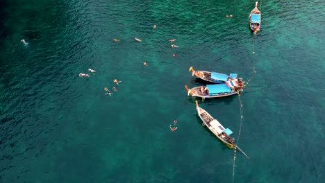 Turistas-Nadando-Desde-Botes-De-Cola-Larga-Cerca-De-Una-Isla-Tropical