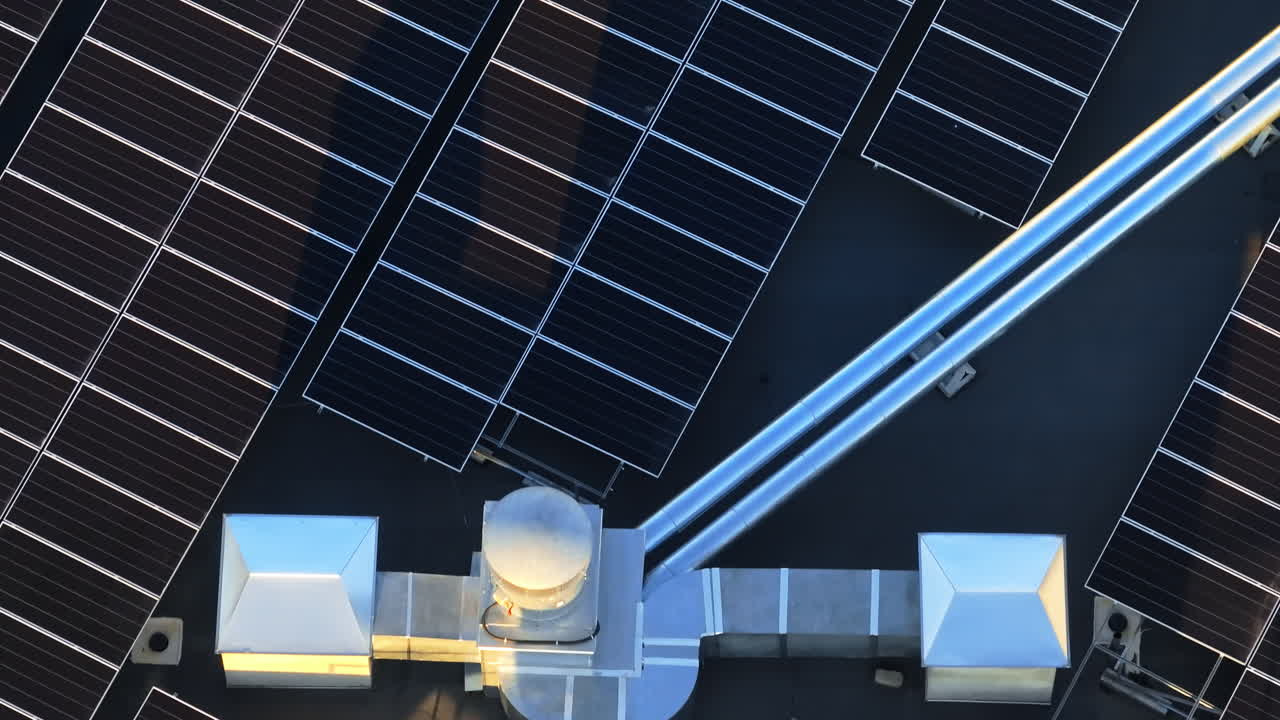 Aerial drone view of solar panels at sunset. Photovoltaics on top of the roof of the building. Alternative electricity source. Concept of sustainable resources