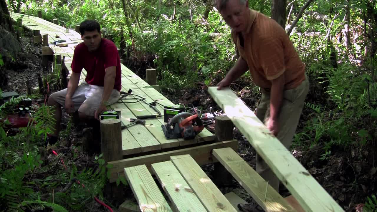 padre e hijo trabajan en una pasarela de madera a través de los everglades