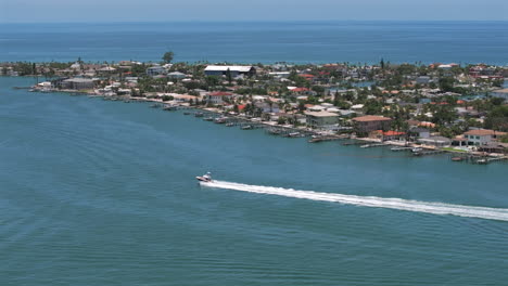 drone shot of speeding boat on the intracoastal channel of st pete beach in florida with waterfront homes on blue water, capturing serene coastal living, marina lifestyle, and scenic paradise