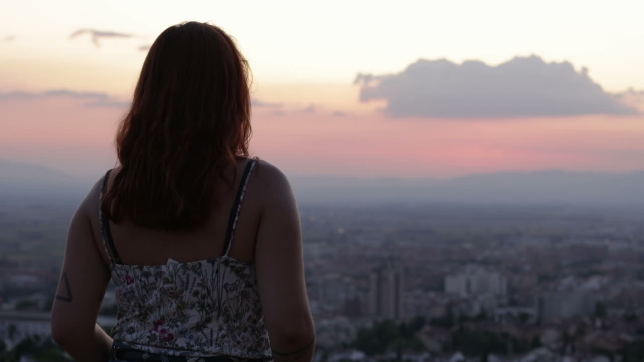 Woman overlooking city at sunset