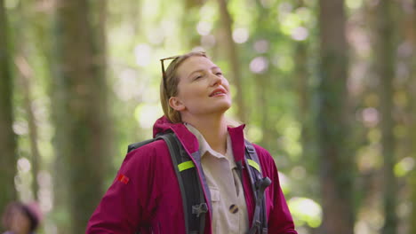 woman closing eyes enjoying peace with female friends on holiday hike through woods together